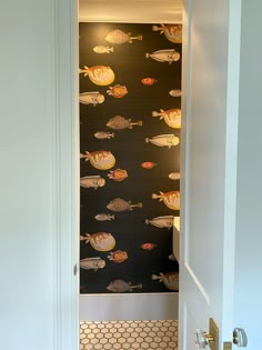 an open door leading to a bathroom with fish on the wall and tiled flooring