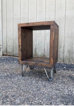 a small wooden box sitting on top of metal legs in front of a white wall