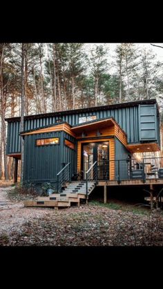 a house made out of shipping containers in the woods with stairs leading up to it