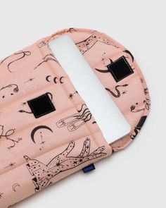 an open laptop computer sleeve on top of a pink surface with black and white drawings