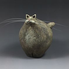 a cat statue sitting on top of a gray surface with it's eyes closed