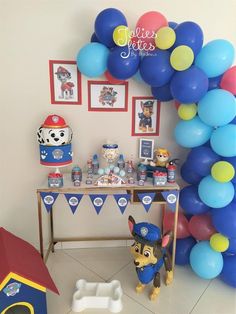 a birthday party with balloons and toys on the table, including a paw patrol cake