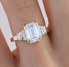 a woman's hand with an engagement ring and three baguettes on it