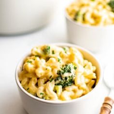 two bowls filled with macaroni and cheese on top of a white countertop