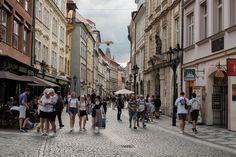 many people are walking down the street in an old european city with cobblestone streets