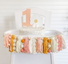 a white cake sitting on top of a table covered in crocheted tassels