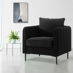 a black chair sitting in front of a window next to a table with a potted plant