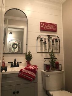 a white toilet sitting under a bathroom mirror next to a christmas decoration on the wall