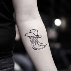 a woman's arm with a cowboy hat and boot tattoo on the left forearm