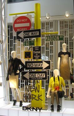 mannequins and street signs are displayed in a window