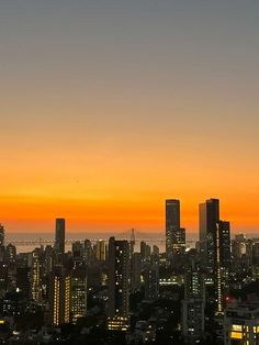 the city skyline is lit up at night with bright orange and yellow colors in the sky