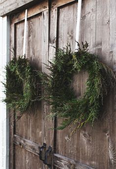 two wreaths hanging on the side of a wooden door