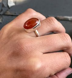 A rich dark blood red orange carnelian has been set in sterling silver with a handmade ring band from sterling silver half dome wire. This stone has inner crystals of differing color that show throughout-it is not a solid blood red orange. The stone has been set horizontally (east to west) and is 13mm x 18mm in size and about 5-6mm in height. It is also available in a vertical (north to south) setting. Made to order! Chose your size and setting direction at checkout! Carnelian brings out hidden Oval Carnelian Jewelry With Polished Finish, Polished Oval Carnelian Jewelry, Handmade Oval Carnelian Ring, Orange Carnelian Oval Cabochon Jewelry, Handmade Orange Carnelian Rings, Orange Carnelian, Carnelian Jewelry, Carnelian Ring, Dark Blood