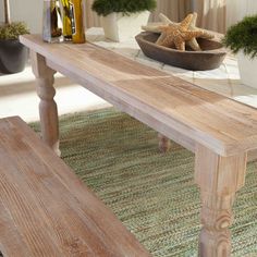 a wooden table sitting on top of a rug next to a bowl filled with plants