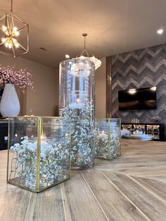 three glass vases filled with flowers on top of a wooden table