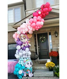 a bunch of balloons that are on the ground in front of a house with flowers