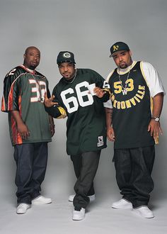 three men standing next to each other in front of a gray background wearing green and yellow jerseys