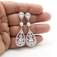 a person is holding two pairs of diamond and pearl earrings