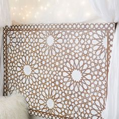 a bed with white sheets and pillows on top of it next to a wall covered in lights