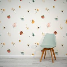 a chair sitting in front of a wall with flowers on it