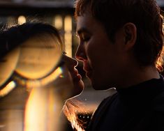 a man and woman kissing each other in front of a building with the sun shining on them