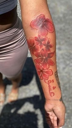 a woman with a tattoo on her arm holding onto a red and white flowered wrist