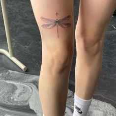 a woman's legs with a dragonfly tattoo on them