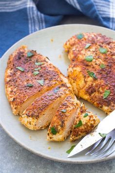 two pieces of chicken on a plate with a knife and fork