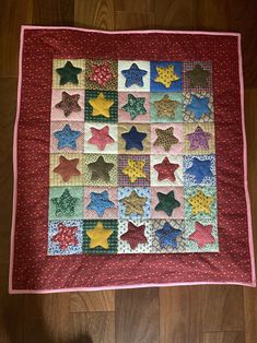 a quilted blanket with stars on it sitting on top of a wooden floor next to a person's feet