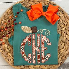 a green shirt with an orange bow is sitting on a basket next to some berries