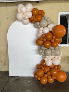 an arch with balloons attached to it in front of a wall that is painted orange and white