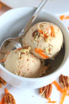 two scoops of ice cream in a bowl with pecans and carrots on the side