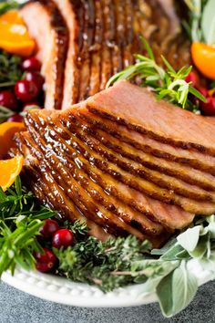 meat and vegetables on a plate with oranges, cranberries, and herbs