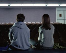 two people sitting on the floor in front of an empty room with rows of seats