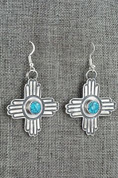 These turquoise and sterling silver New Mexico Zia symbol shaped earrings were made by Navajo silversmith Kevin Billah. The backs are signed KB and stamped sterling.Length: 2 1/4"Width: 1 3/8"Free shipping on all orders! We ship with USPS and always include tracking. All orders ship within a day of payment.Returns are accepted up to 30 days after you receive your order. Just send us a message. Our shop offers cash back or store credit. The item must be returned in new condition. Turquoise Concho Dangle Jewelry, Blue Concho Dangle Earrings, Traditional Turquoise Sterling Silver Earrings, Traditional Turquoise Jewelry With Concho, Traditional Turquoise Concho Jewelry, Nickel-free Turquoise Southwestern Earrings, Turquoise Nickel-free Southwestern Earrings, Southwestern Style Stamped 925 Drop Earrings, Sterling Silver Turquoise Concho Jewelry