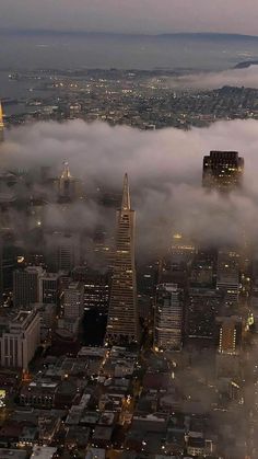 an aerial view of the city with skyscrapers and fog in the air at dusk