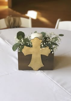 a wooden box with flowers and a cross on it sitting on top of a table