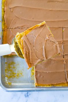 a person is spreading frosting on a cake in a pan with a spatula