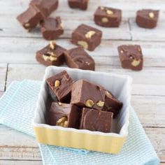 a white bowl filled with chocolate and nuts on top of a blue towel next to a wooden table