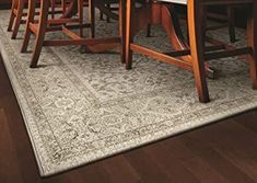 a dining room table with chairs and a rug on the floor in front of it