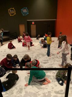 children are playing in the sand at an indoor play area with snow on the ground