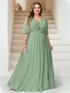 a woman standing in front of stairs wearing a green dress and holding a white purse