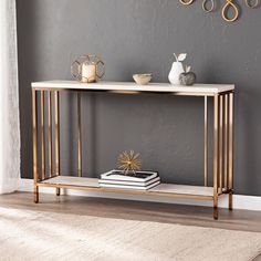 a console table with a white marble top and gold metal legs, against a gray wall