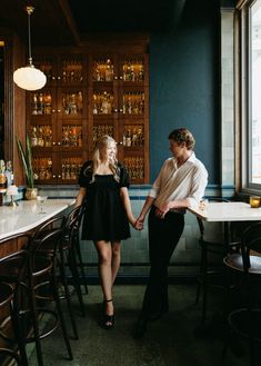 two people standing in front of a bar holding hands