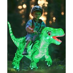 a young boy riding on the back of a green dinosaur toy