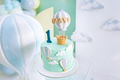 a blue and white cake with hot air balloons on top