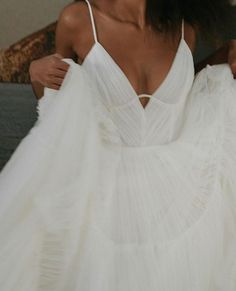 a woman in a white dress is smiling and holding onto the back of her wedding gown