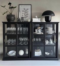 a black cabinet filled with glasses and plates