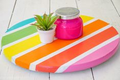 a potted plant sitting on top of a multicolored wooden tray with a jar