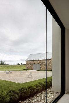 an empty courtyard with tables and chairs is seen through the glass walls of this house